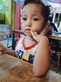 Portrait of cute baby girl on table