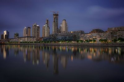 Reflection of skyscrapers in river against sky