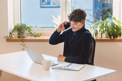 Goal-oriented businessman is on the phone with his supervisor, jotting notes in his diary