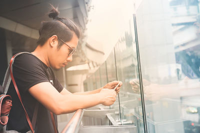 Side view of young woman looking through window