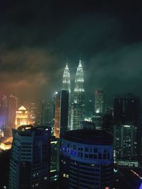 Illuminated buildings in city against sky at night