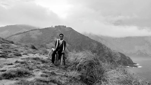 Portrait of man standing on field against sky