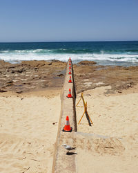 Scenic view of sea against clear sky with traffic cones