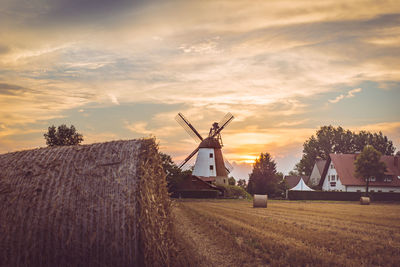 Traditional windmill on field against sky at sunset