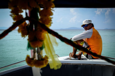 Man in boat sailing on sea against sky