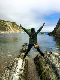 Woman gesturing peace sign while standing against lake