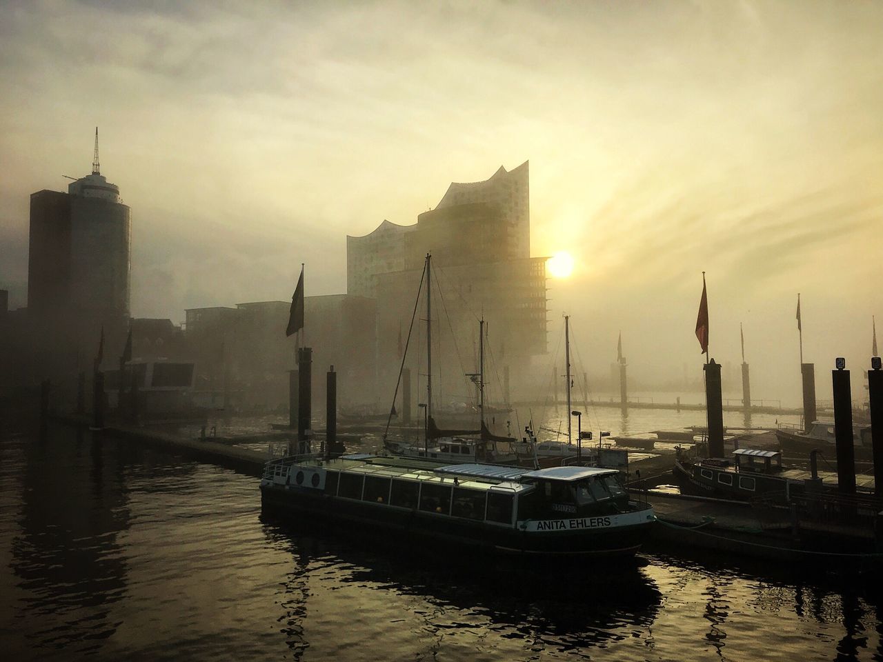 nautical vessel, architecture, sunset, building exterior, water, built structure, waterfront, outdoors, sky, no people, skyscraper, moored, harbor, mast, city, day, cityscape, nature