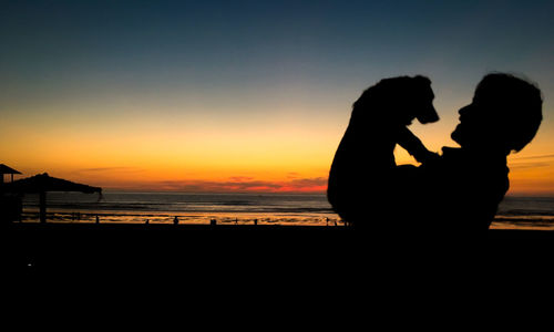 Silhouette couple on beach against sky during sunset