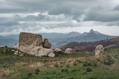 Stone wall on landscape against cloudy sky