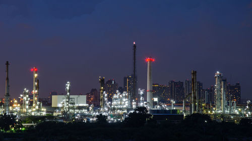 Illuminated factory against sky at night