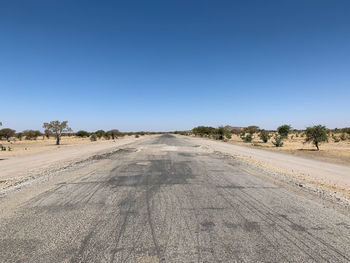 Road amidst trees against clear sky