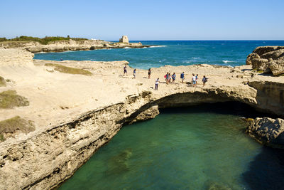 People on rock formation at shore