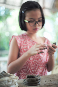 Midsection of woman holding eyeglasses while sitting on table