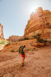 Lone female hiker walks on a dried river bed under red canyon cliffs