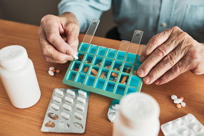 Senior man organizing his medication into pill dispenser. senior man taking pills from box