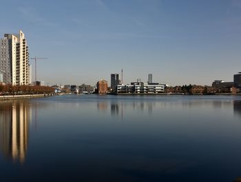 Water by buildings in city against sky