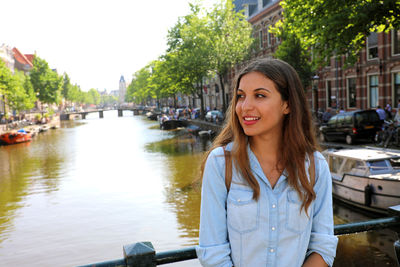 Portrait of smiling young woman against canal