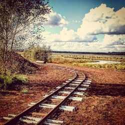 Railroad track by landscape against sky