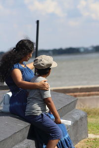 Rear view of people sitting by water