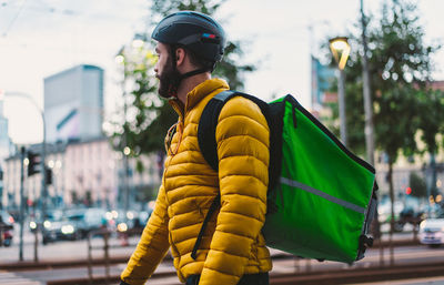 Man standing with bicycle on street in city