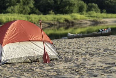 Tent on beach with canoes by river