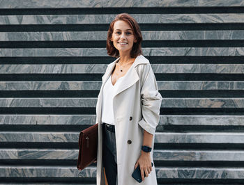 Portrait of young woman standing against wall