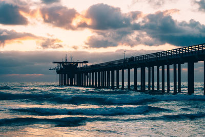 Pier on sea against cloudy sky