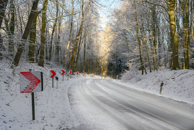 Road amidst trees in forest during winter