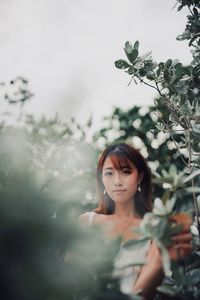 Portrait of beautiful young woman standing by plants