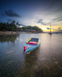 Boats in lake against sky during sunset