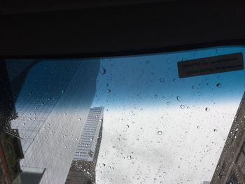 Close-up of wet window against sky