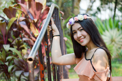 Portrait of young woman standing against plants