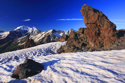 Scenic view of snow covered mountains against blue sky