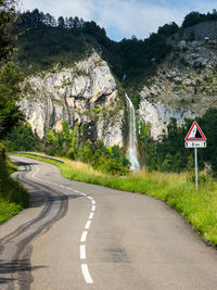 Curvy country road by a large waterfall in the mountains