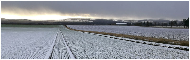 Snow covered road by mountains against sky