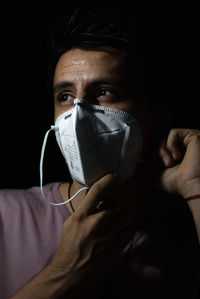 Close-up portrait of man covering face against black background