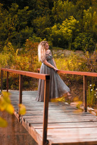 Woman wearing evening gown while standing footbridge against plants