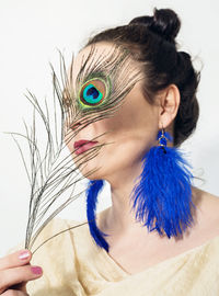 Portrait of woman holding feather against white background