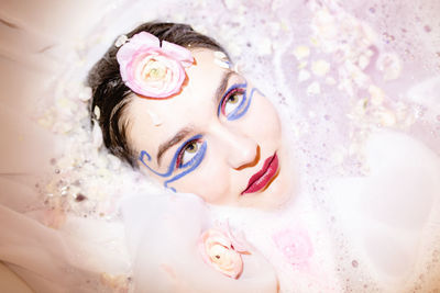 Young woman wearing make-up while relaxing in bathtub