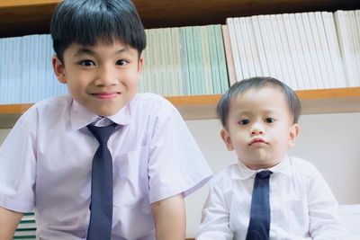 Portrait of boys against bookshelf