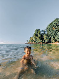 Portrait of smiling woman in sea against sky