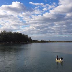 Boat sailing in sea against cloudy sky