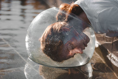 Close-up of woman wearing glass container at lake