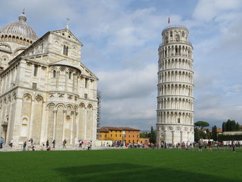 Leaning tower of pisa and cathedral against cloudy sky at piazza dei miracoli