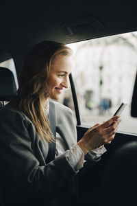 Woman using mobile phone in car