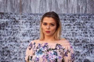 Portrait of beautiful young woman standing against wall