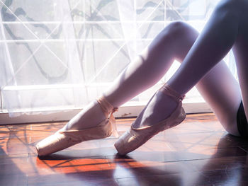 Low section of ballet dancer on window sill