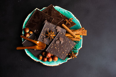 High angle view of chocolate bars with spices and nuts in plate on table