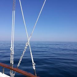 Close-up of sailboat in sea against clear blue sky
