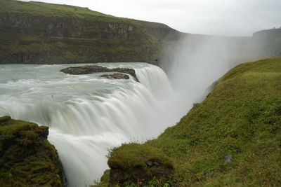 Scenic view of waterfall against sky